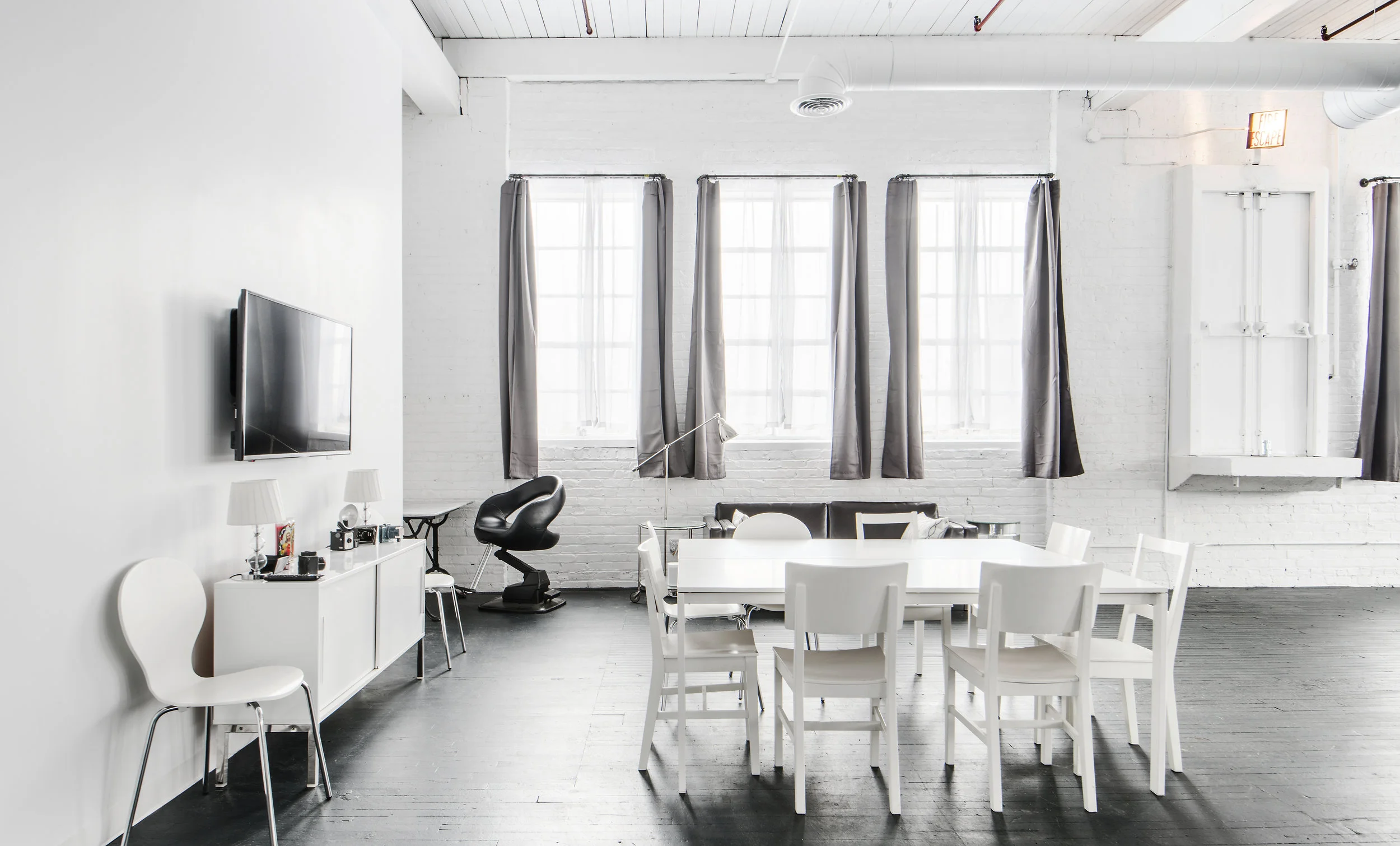 White client area at Stopover Studios with table, chairs, lounge seating, and daylight